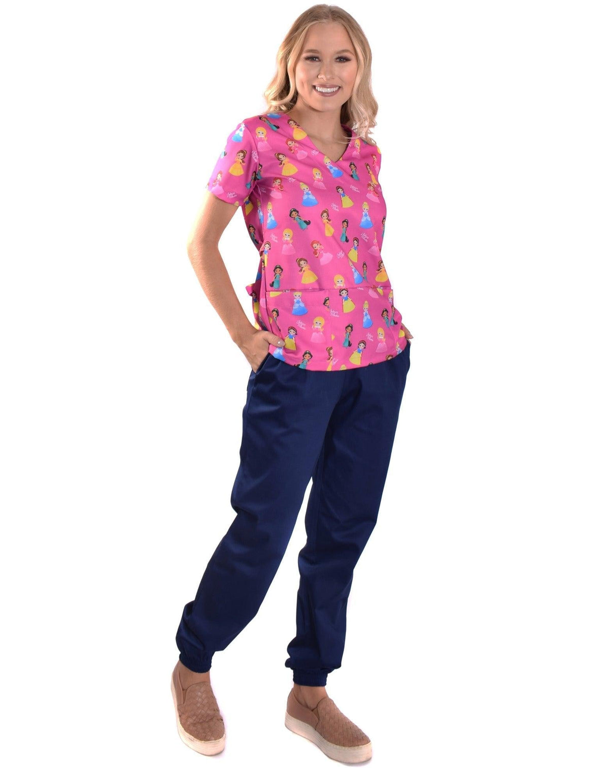 Scrub feminino Funny Princesas levemente de lado, blusa rosa estampada e mão no bolso da calça azul marinho — foto 3
