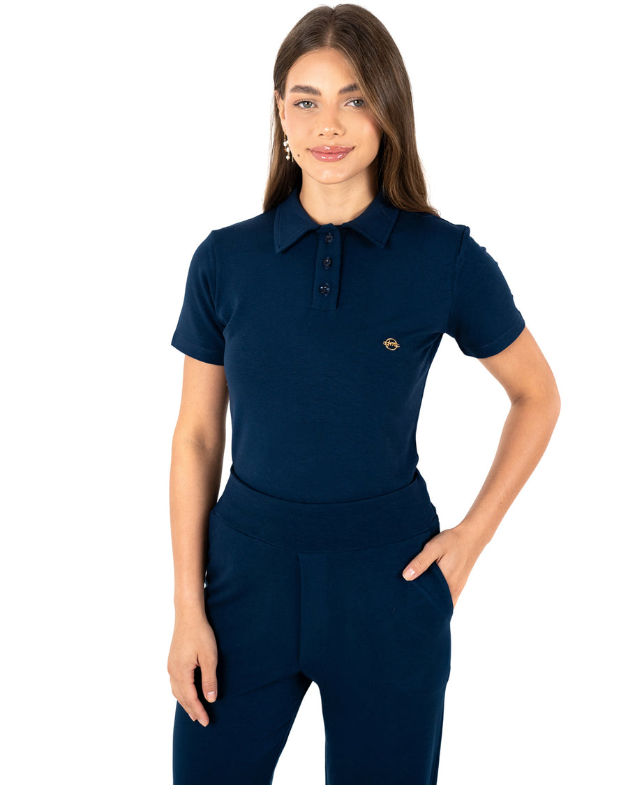 Scrub feminino Ivy moletinho azul marinho, detalhe da gola polo com botões e mão no bolso da calça de cós largo