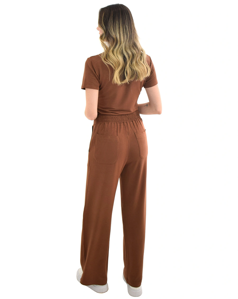 Scrub feminino Ivy moletinho marrom de costas, calça pantalona com cós elástico franzido e bolsos traseiros