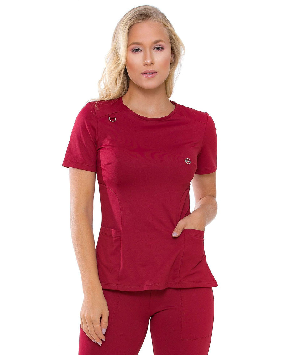 Scrub feminino Lily Soft bordô em meio corpo, gola redonda, argola no ombro e mão no bolso frontal da blusa