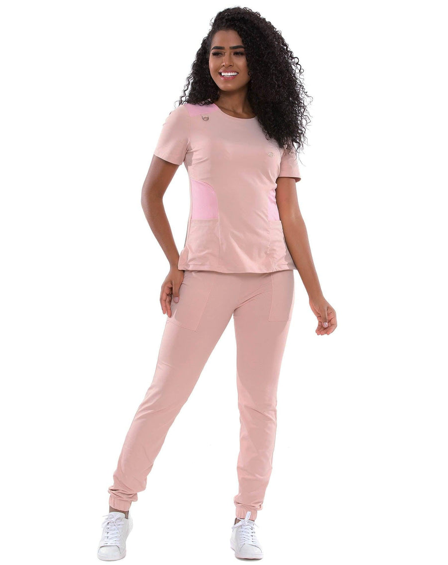 Scrub feminino Lily Soft nude com rosa de frente, blusa com recortes rosa na lateral e calça jogger nude