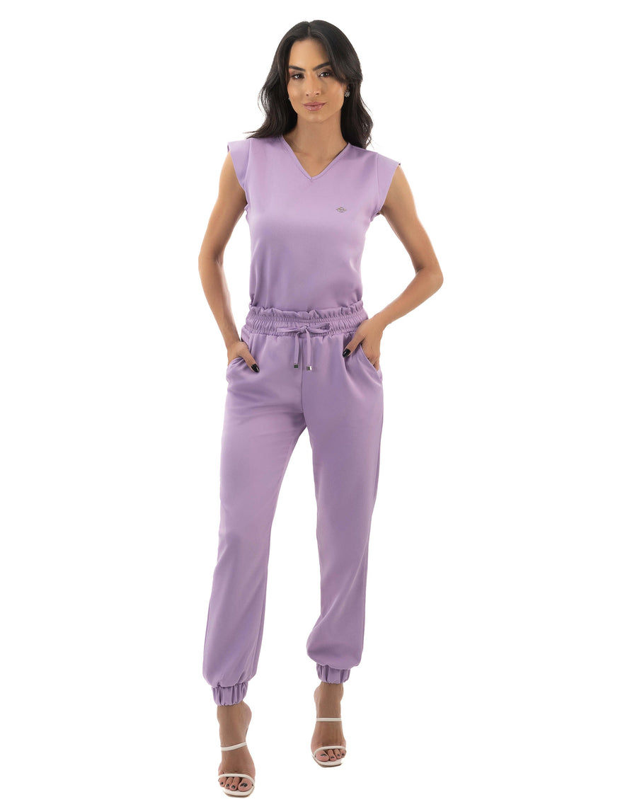 Scrub feminino Luna lavanda de corpo inteiro, modelo com as mãos nos bolsos da calça jogger de punho elástico