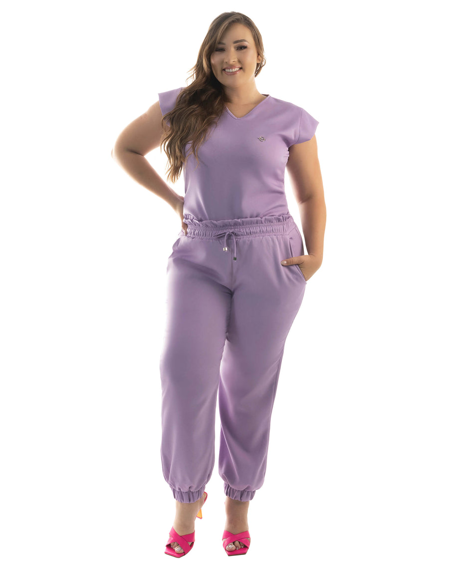 Scrub feminino Luna lavanda em modelo plus size, vista frontal com blusa gola V e calça jogger com cordão