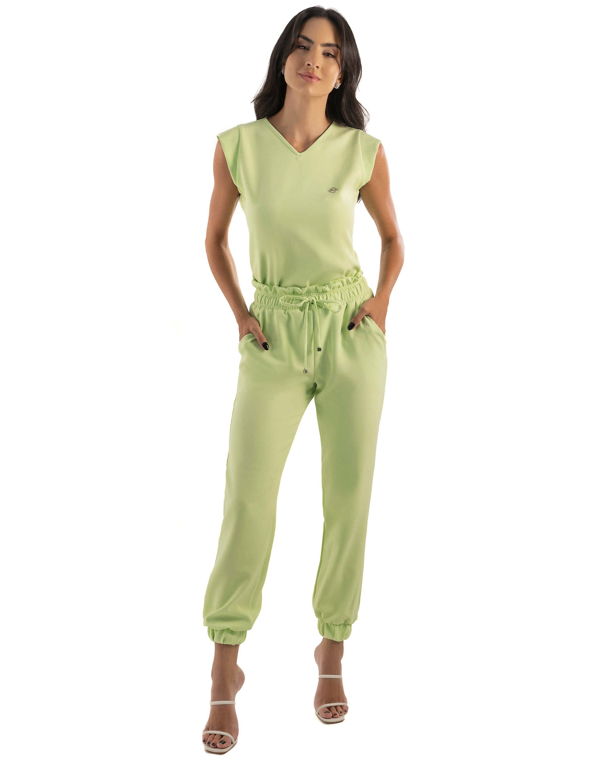 Scrub feminino Luna verde pistache, modelo de corpo inteiro com blusa sem manga gola V e mãos nos bolsos