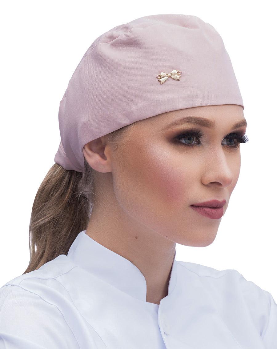 Touca bandana feminina nude em modelo, vista lateral, tecido liso rosa claro com lacinho dourado na frente