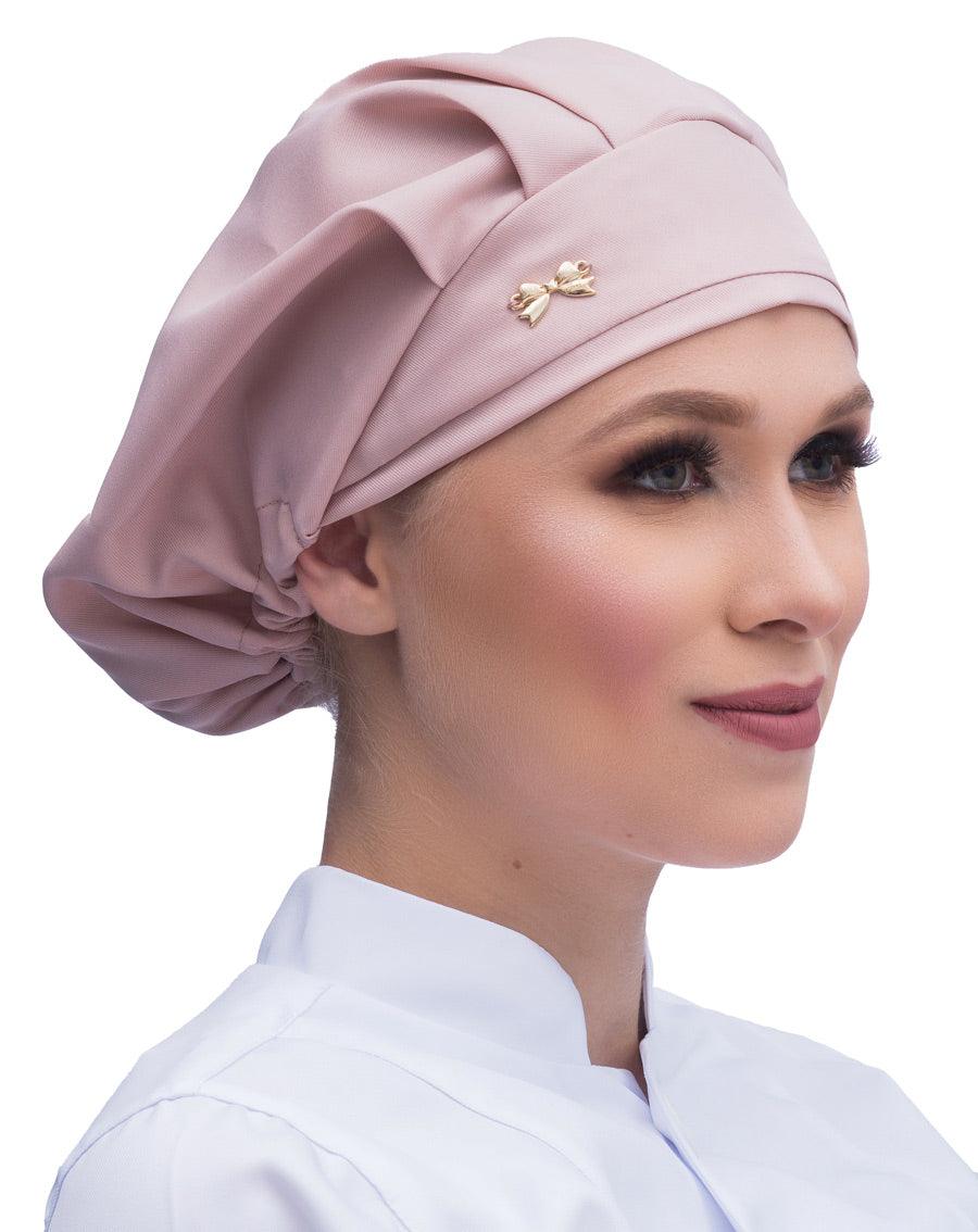 Touca elástico feminina nude rosado em modelo, vista lateral com pregas no topo e lacinho dourado na frente