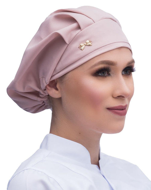 Touca elástico feminina nude rosado em modelo, vista lateral com pregas no topo e lacinho dourado na frente