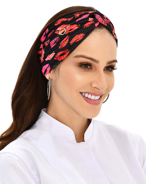 Turbante feminino Mil Beijos preto em modelo sorrindo, vista frontal, nó torcido e estampa de beijos de batom