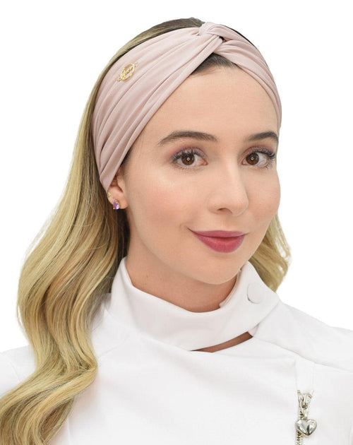 Turbante feminino nude em modelo, vista frontal, nó torcido no topo, tecido franzido e logo dourado