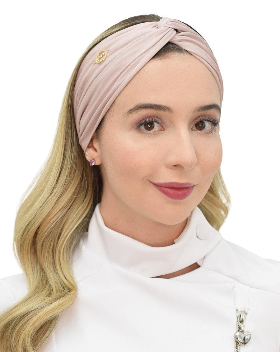 Turbante feminino nude em modelo, vista frontal, nó torcido no topo, tecido franzido e logo dourado