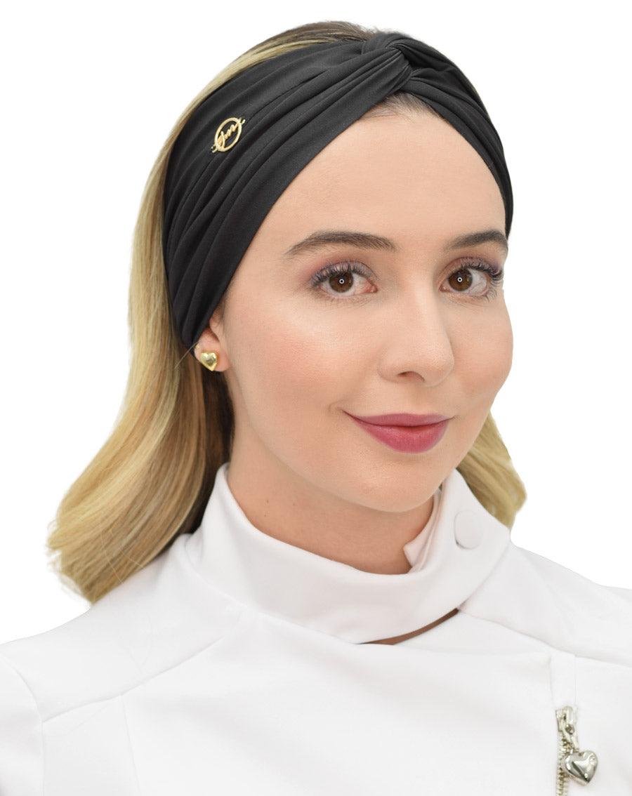 Turbante feminino preto em modelo, vista frontal, nó torcido no topo, tecido franzido e logo dourado — foto 2