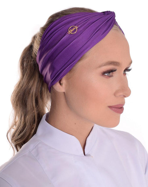 Vista lateral do turbante feminino violeta em modelo de rabo de cavalo, mostrando franzido do tecido e pin dourado
